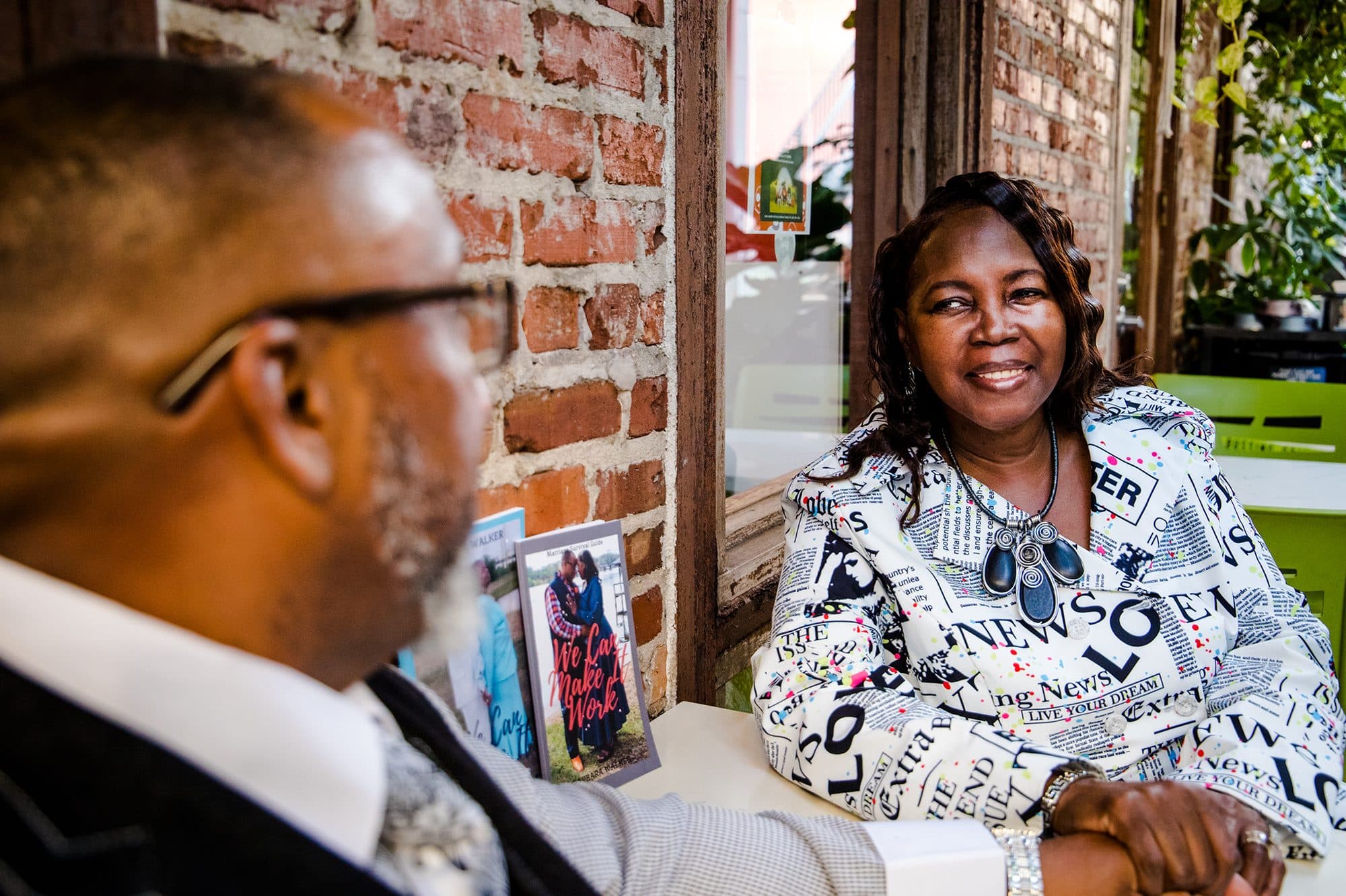 A couple laughing at a table in a brick-walled cafe
