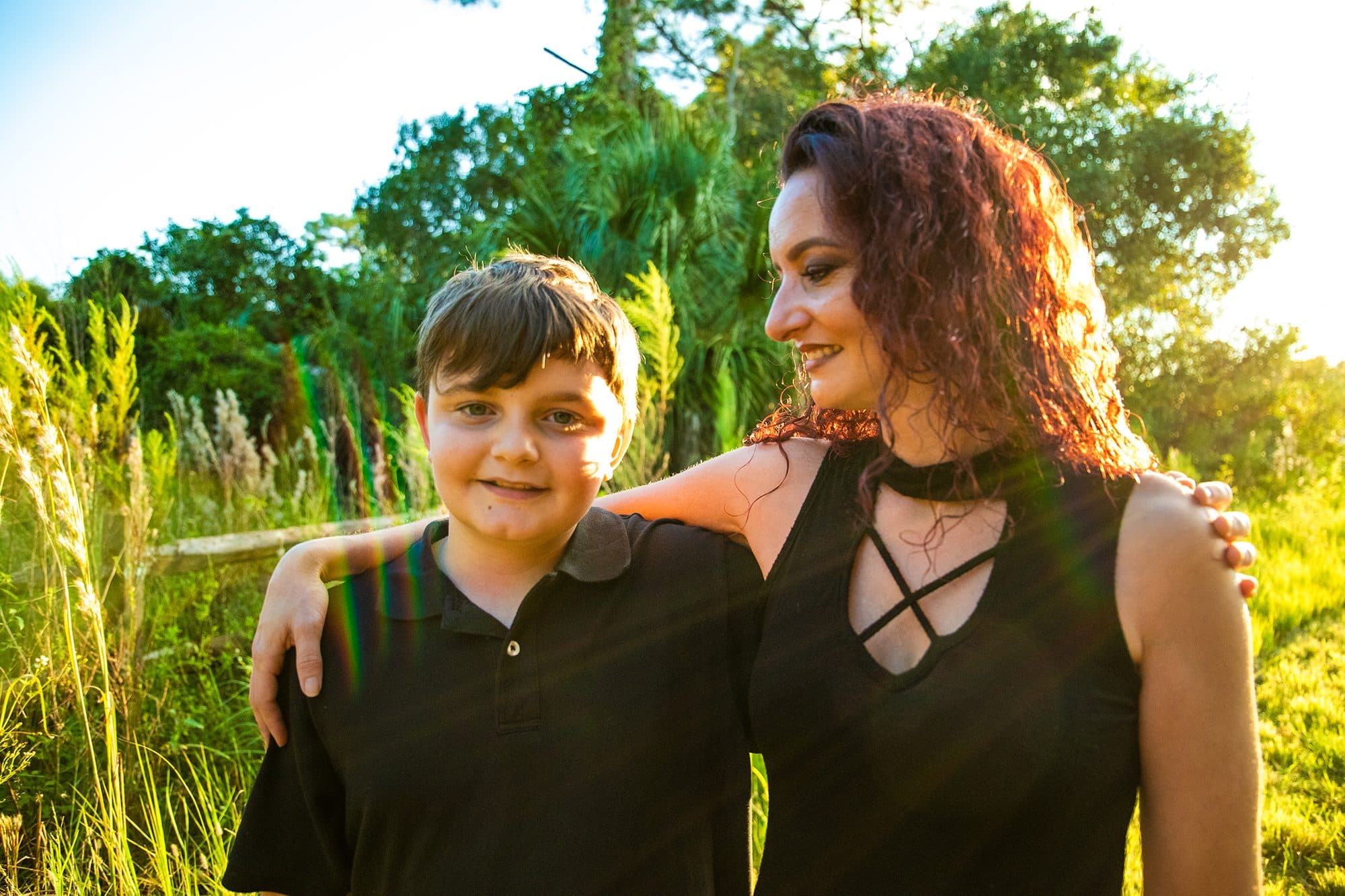 A boy leaning into his mother in golden light