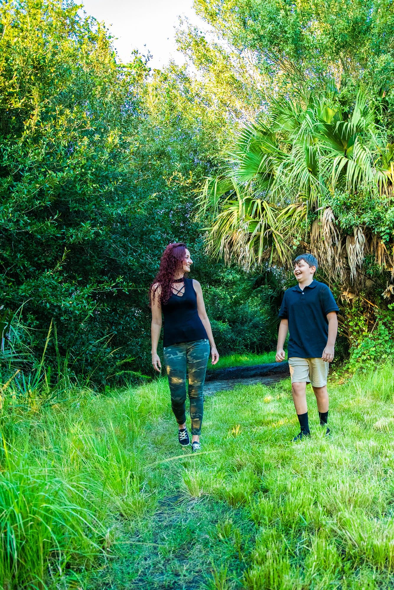 Mother and son walking through a sunlit path in the palms