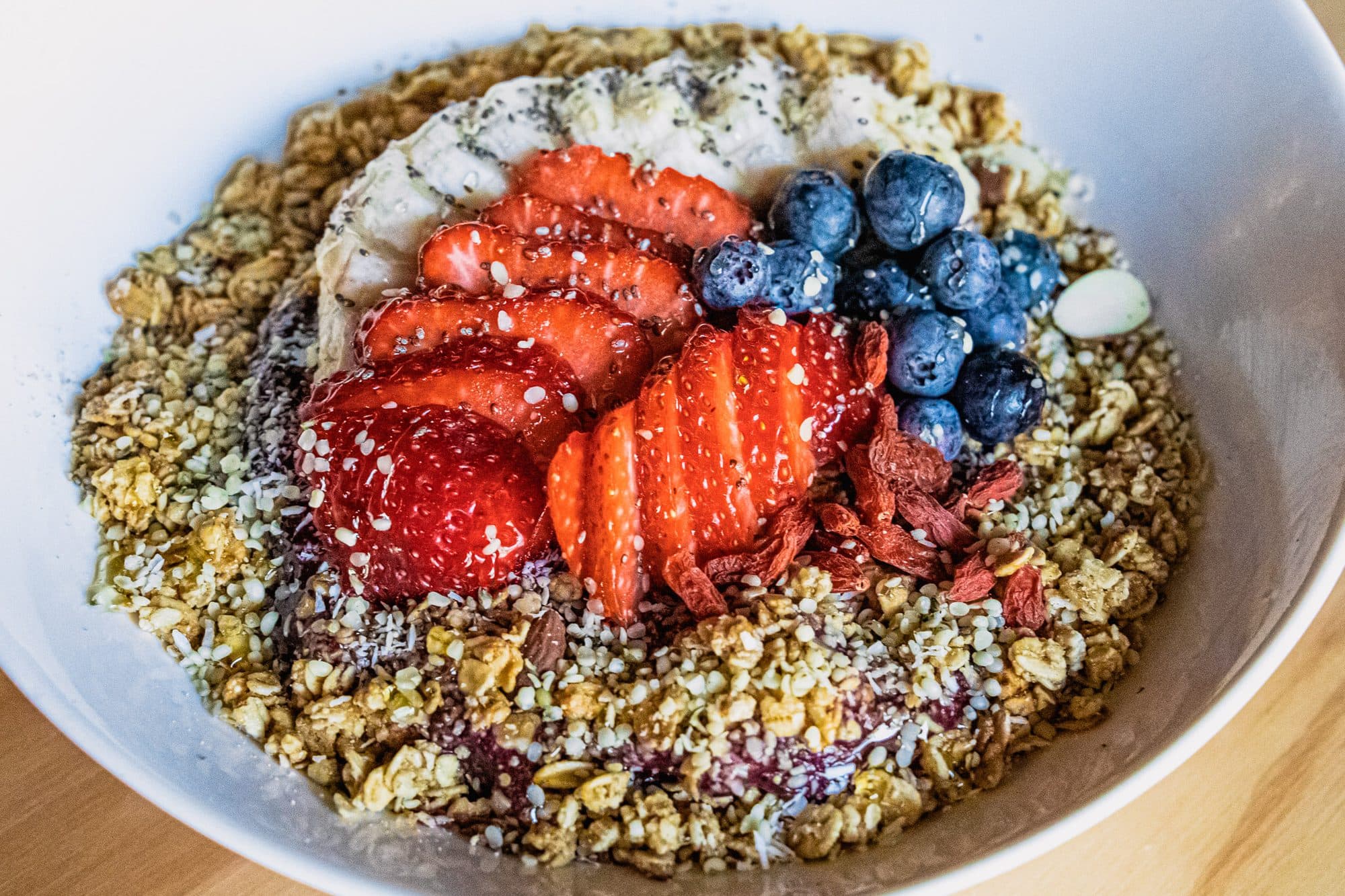 Overhead granola bowl with strawberries, blueberries and banana