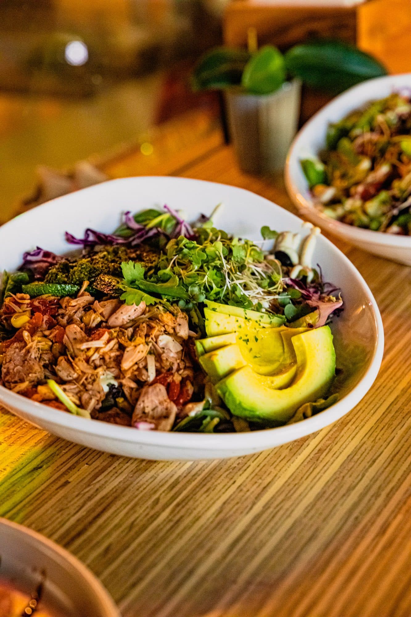 A grain bowl with avocado and purple cabbage on a wooden counter