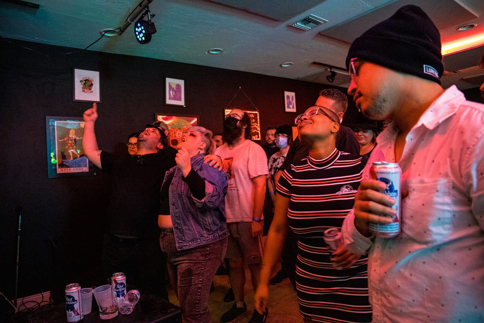 Concert-goers in beanies watching the stage under pink light