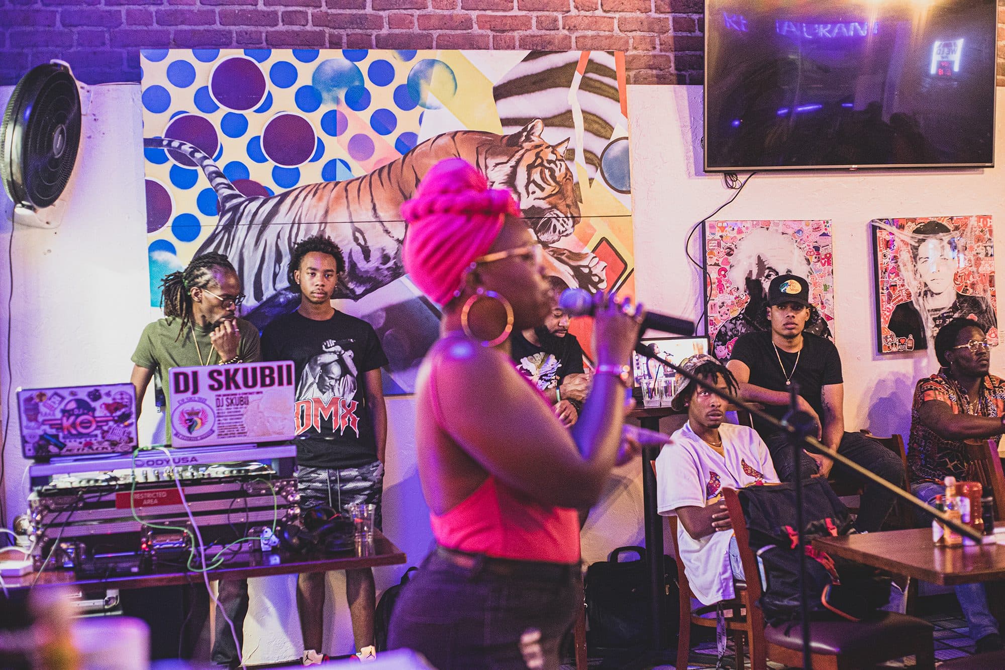 A DJ and MC performing in a room of murals