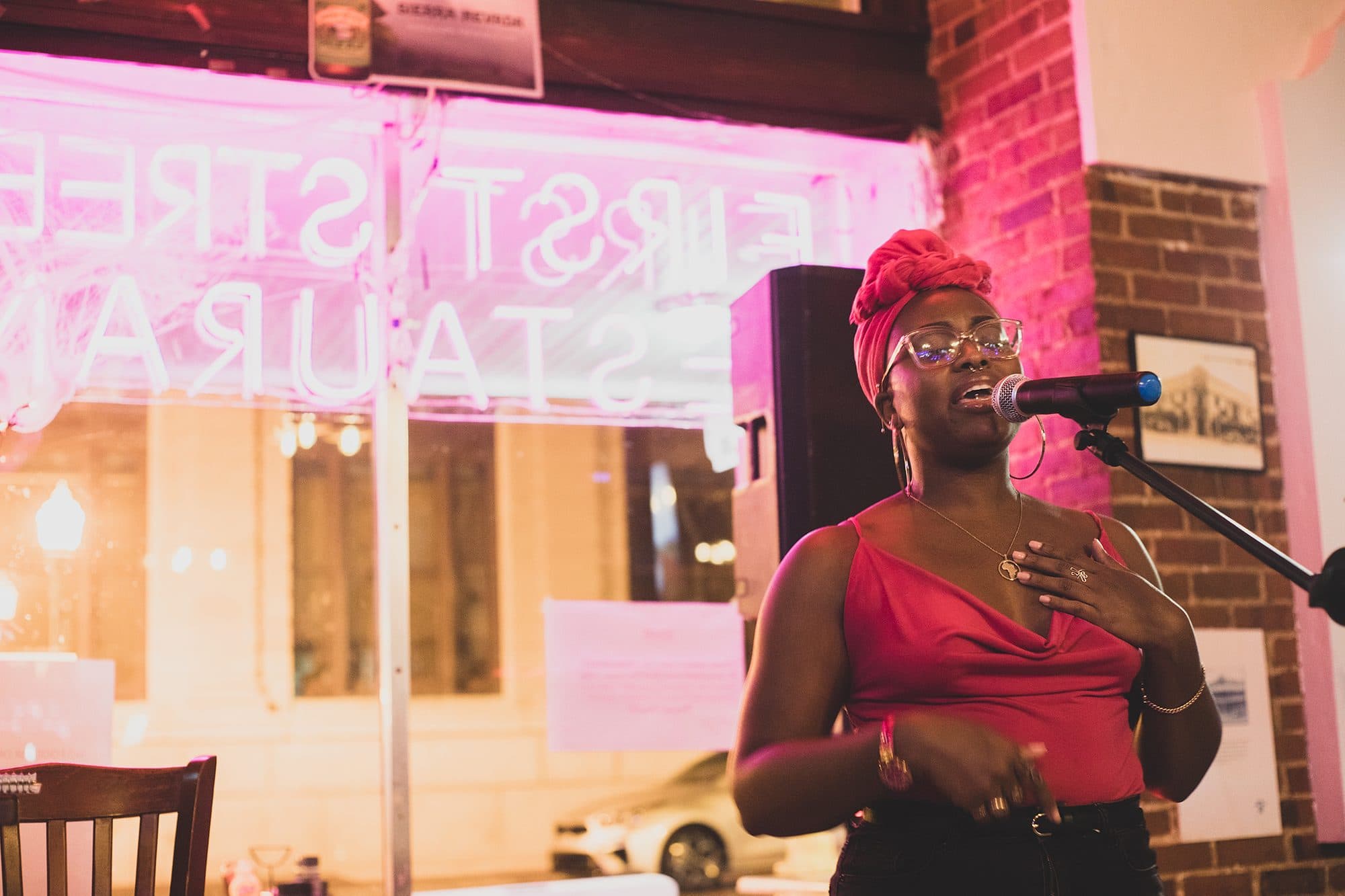 A singer in red at the mic, neon glowing behind her